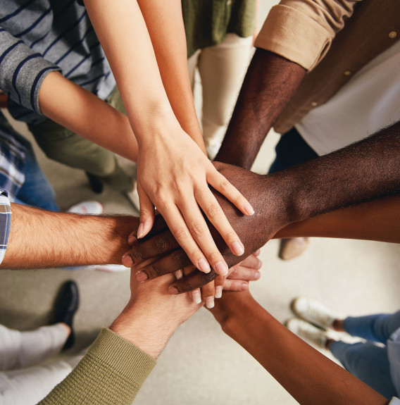 the hands of six people all meeting in the center viewed from above