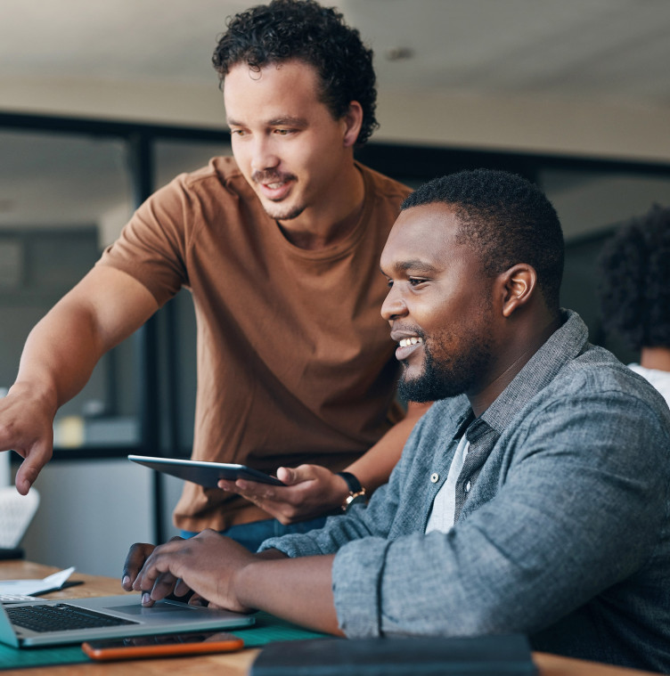 two young black male professionals looking at a laptop screen together