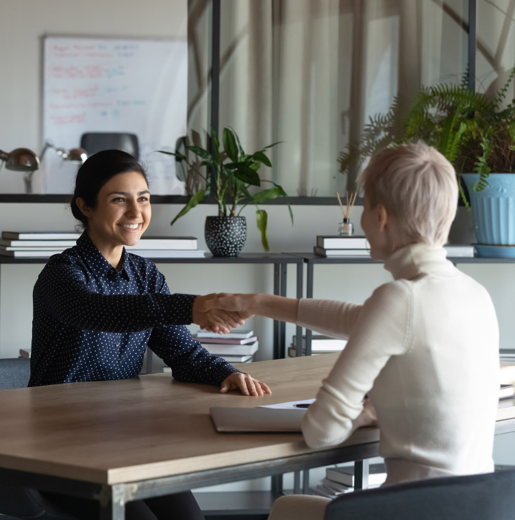 two women shaking hands across a meeting table